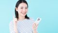 スマホを手に笑顔で指さす女性